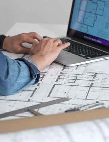 real-project-planning-by-qualified-professionals Professional engineer reviewing home addition plans and material specifications on a laptop during project planning.